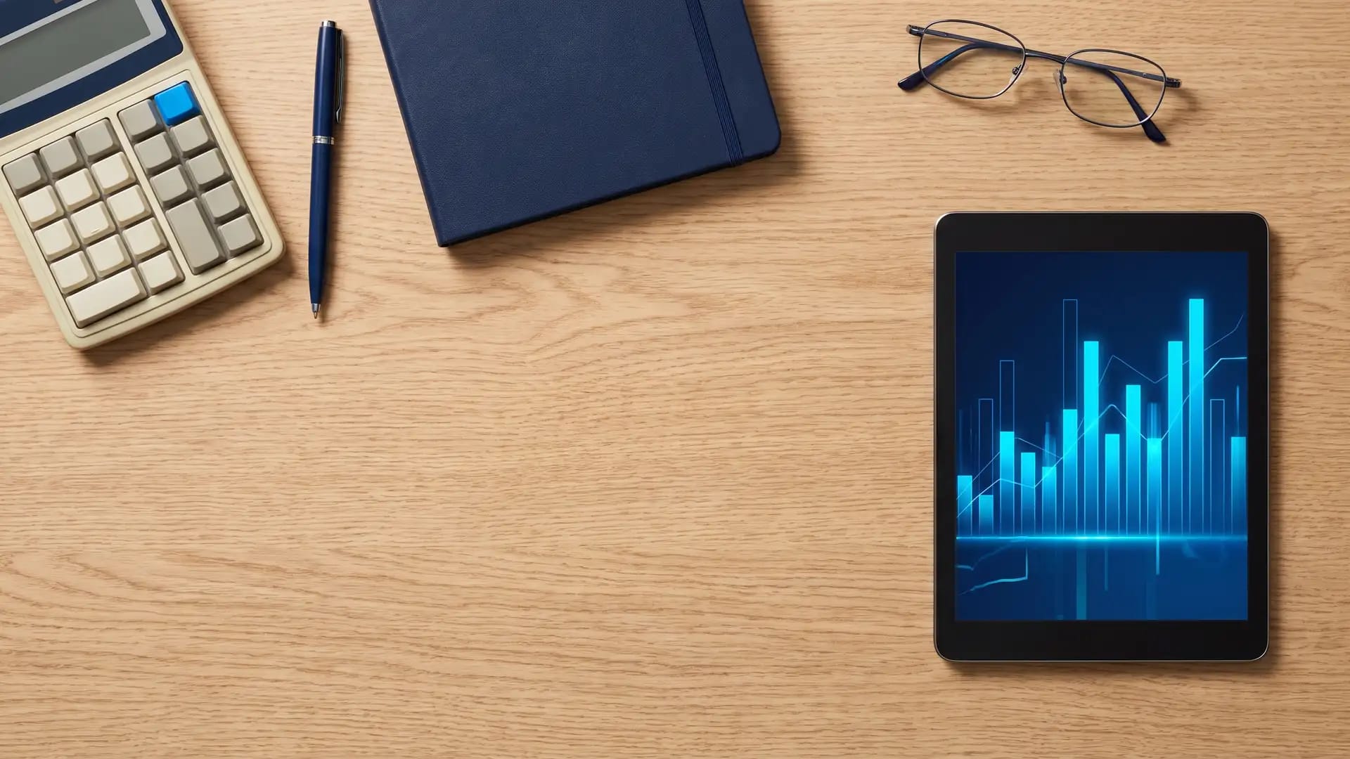 An accountant's desk with calculator, notebook and a tablet showing financial charts