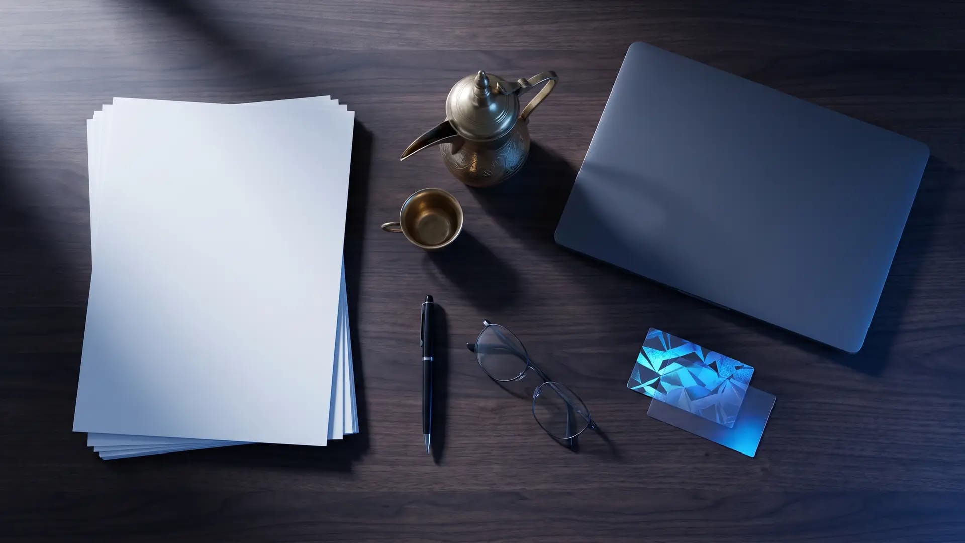 Overhead view of a dark wood desk with blank documents, a closed laptop, an Arabic coffee pot and a security certificate card with blue holographic foil